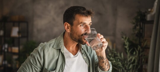 Ein Mann trinkt ein Glas Wasser.