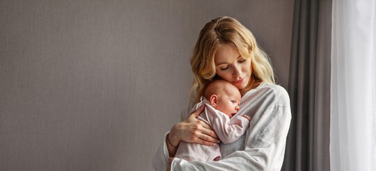 Eine junge Frau hält ihr Baby auf dem Arm.