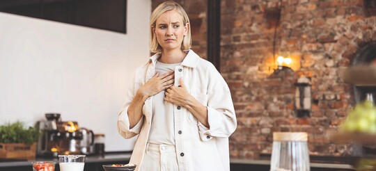 Frau schaut besorgt und fasst sich mit der Hand an die Brust.