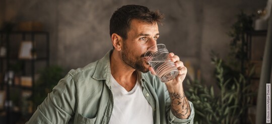 Ein Mann trinkt ein Glas Wasser.
