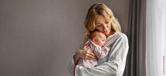 Eine junge Frau hält ihr Baby auf dem Arm.