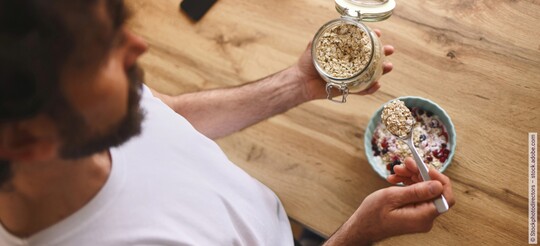 Mann bereitet Müsli mit Haferflocken zu