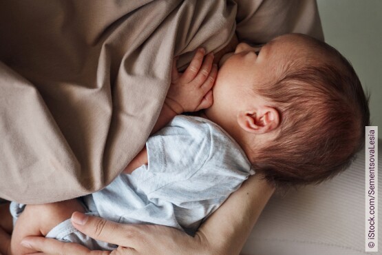 Eine Mama hält ihr Baby im Arm und stillt es.