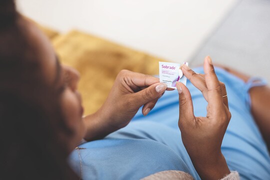 Schwangere Frau holt sich eine Sobrade® Kautablette aus der Verpackung