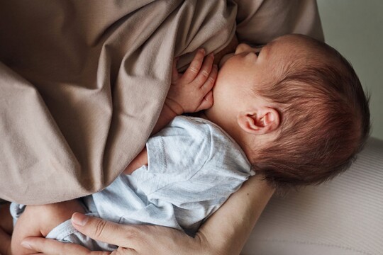 Eine Mama hält ihr Baby im Arm und stillt es.